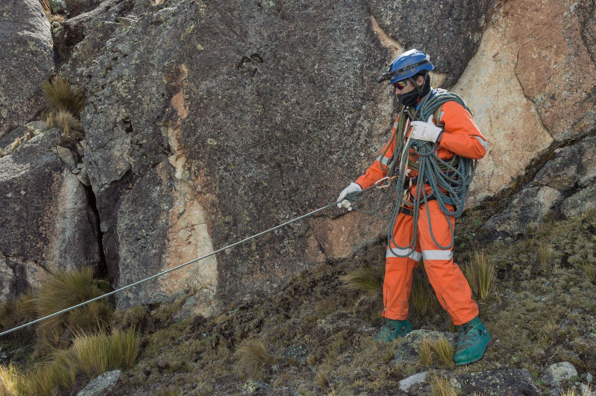 Técnico con equipo de trabajo en cuerda sobre una ladera rocosa